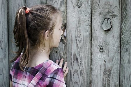 Enfant regarde à traver une palissade